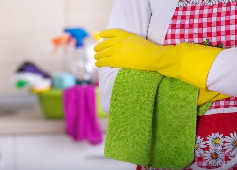Professional cleaner dusting and tidying a kitchen in W1T